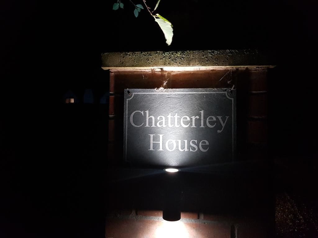 A sign for 'Chatterley House' illuminated in the dark.