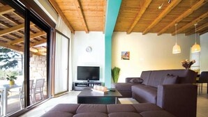 Una sala de estar moderna con un ventanal grande, un televisor de pantalla plana, un sofá y una mesita de centro.