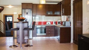 Una cocina moderna con gabinetes de madera oscura, electrodomésticos de acero inoxidable y una isla central con taburetes.