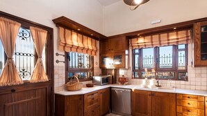 A kitchen with wooden cabinets, a microwave, a sink, and a dishwasher. - Villa Thalassea (Chania)
