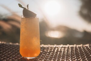 A tall glass with a beverage on a metal surface.