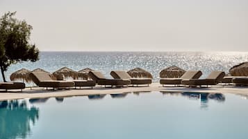 Una piscina al aire libre, sombrillas, sillones reclinables de piscina