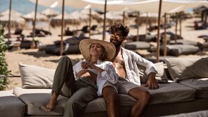 Una pareja descansando en un sofá color arena con vista al mar.