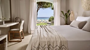 Un dormitorio con una cama grande, una silla, un escritorio y vistas al mar.