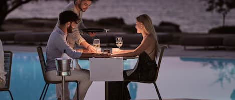 A dining table with two chairs, a waiter, and a woman seated.