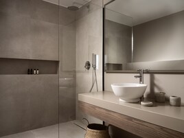 Un bagno moderno con un grande specchio, un lavandino bianco e una cabina doccia in vetro.