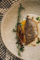 Un piatto con del pesce, una fetta di carne e verdure.