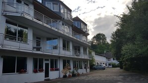 A multi-story hotel with balconies, large windows, and potted plants. - Hotel zur Engelsburg (Hausen)
