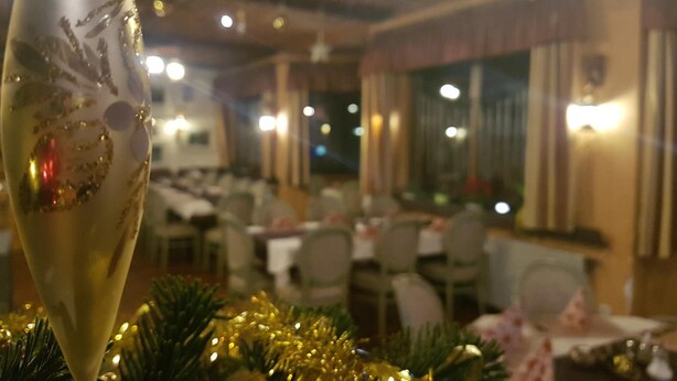 A restaurant interior with tables and chairs, star-shaped ceiling decorations, and a Christmas tree with lights. - Hotel zur Engelsburg (Hausen)