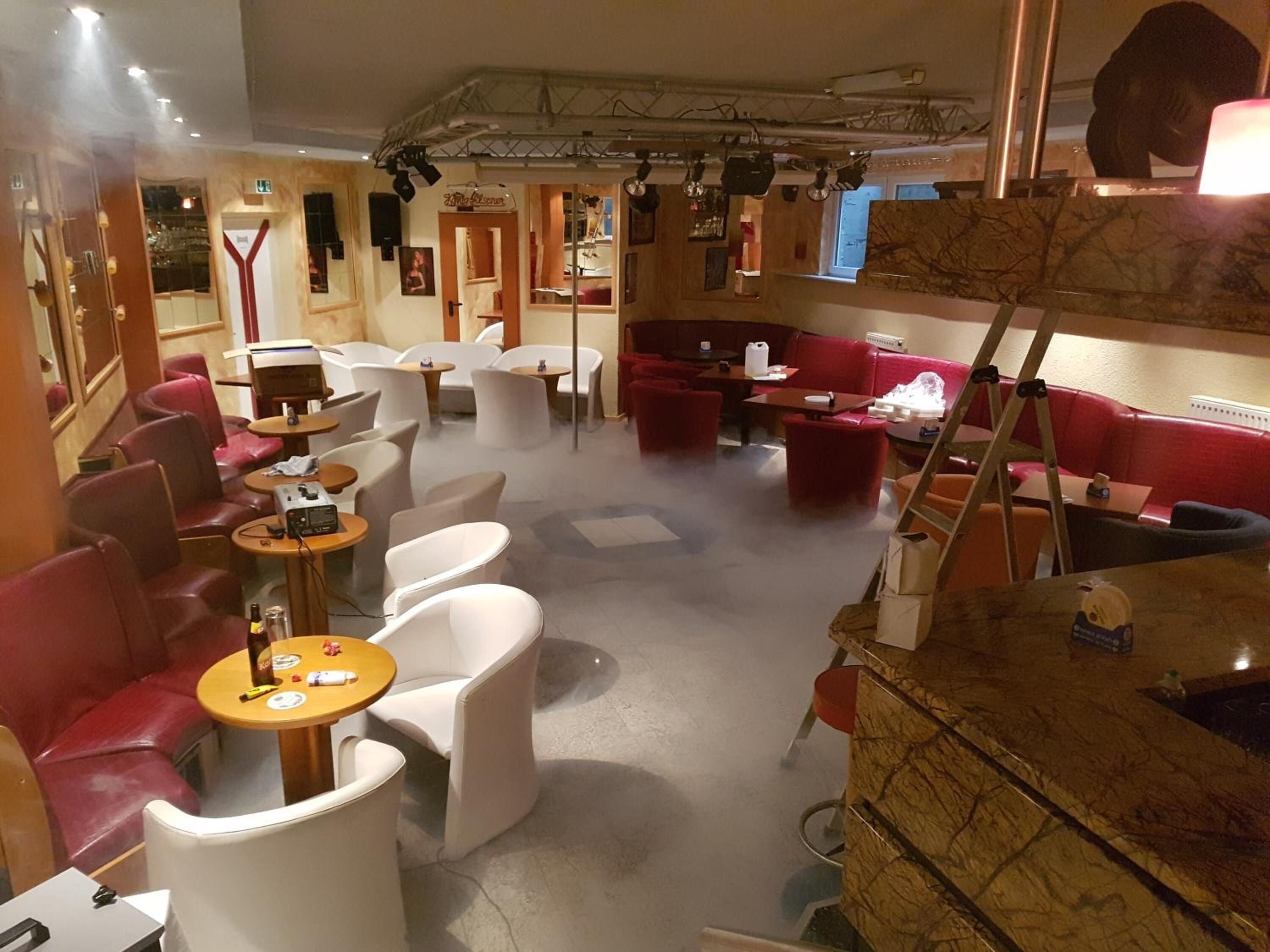 Un interior moderno con asientos rojo y blanco, una zona de bar y un escenario con equipo de iluminación.