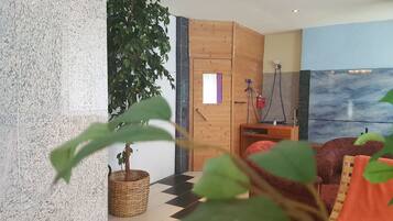 A room with a checkered floor, a large potted plant, a wooden cabinet, and a painting on the wall.