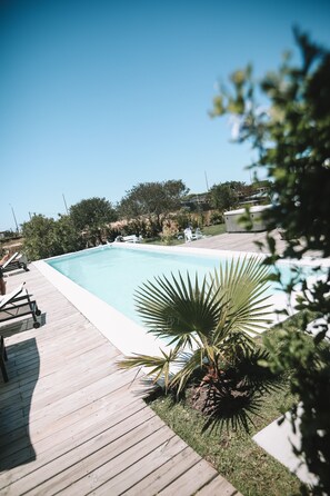 A swimming pool with a wooden deck and lounge chairs.
