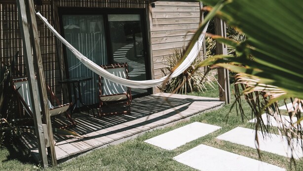 A wooden deck with a hammock, two chairs, and a small wooden structure. - Casa Bikini (Manatiales)