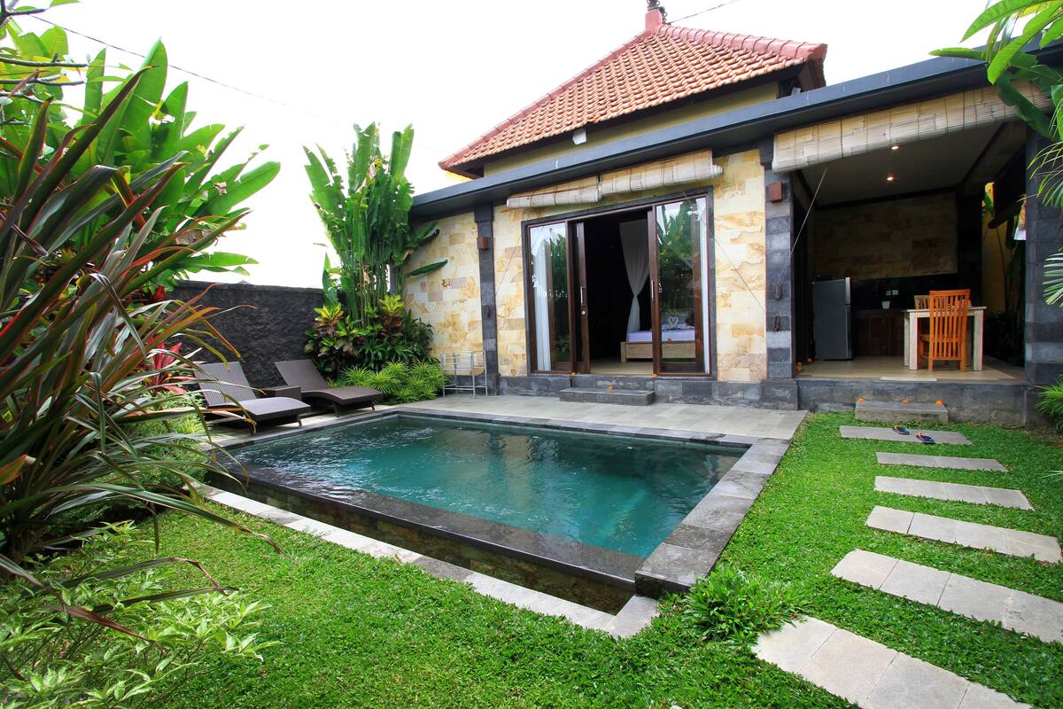 A residential property with a swimming pool, outdoor seating, and a covered patio area.