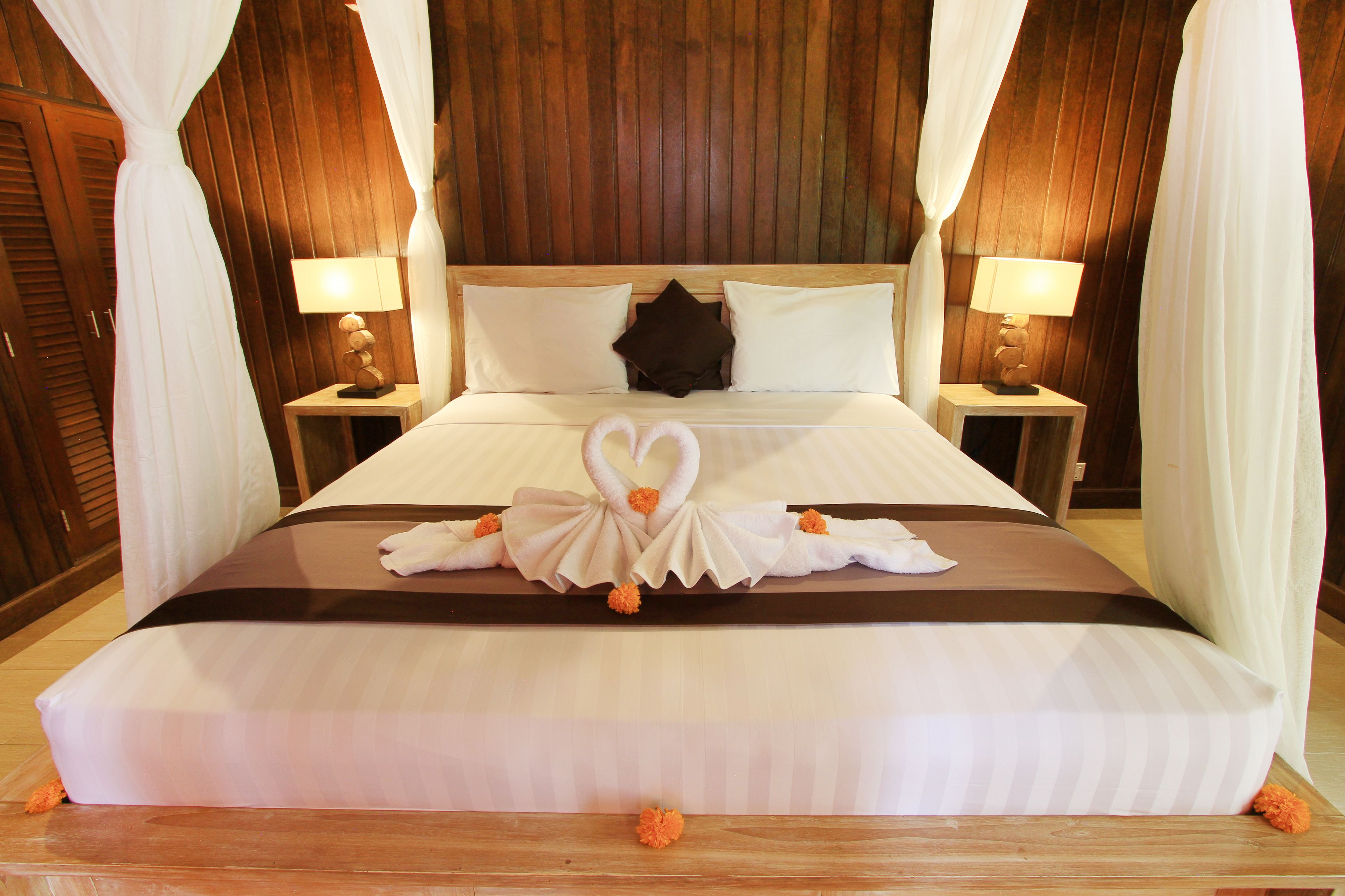 A bed with a decorative swan design, white bedding, and two bedside lamps.
