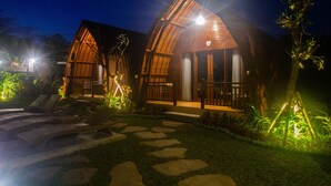A wooden villa with a stone pathway leading to a pool area, surrounded by lush greenery. - Pondok Naya (Ubud)