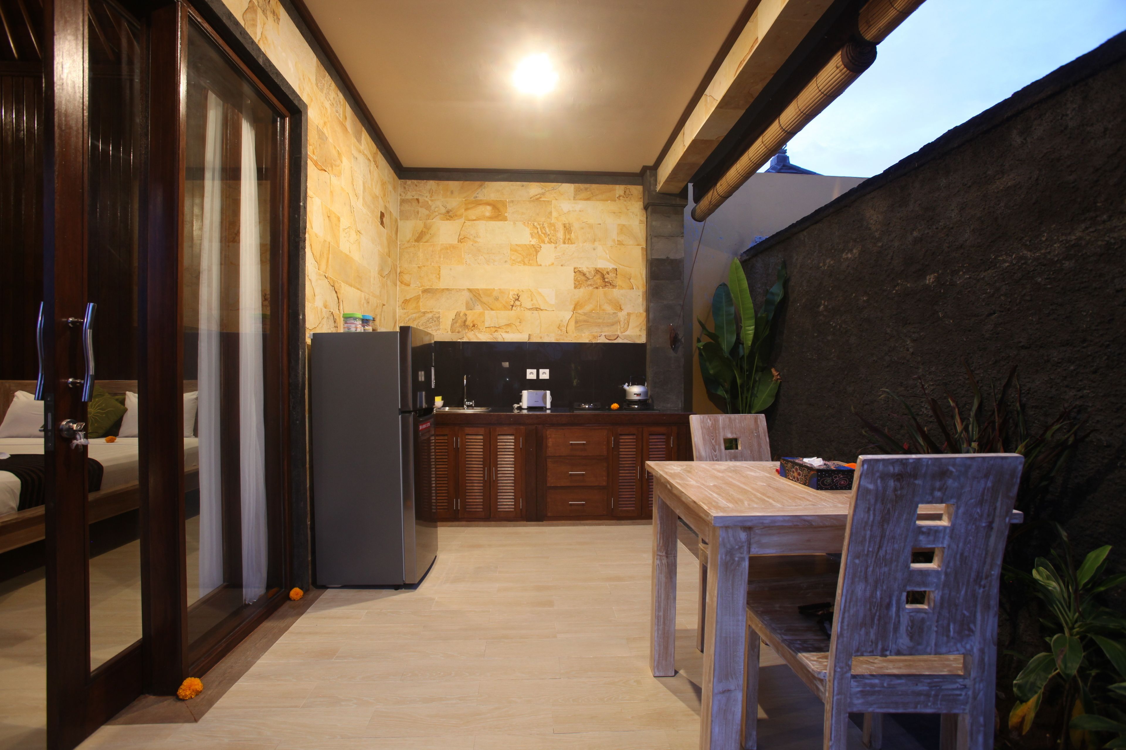 A compact kitchen with a stone backsplash, wooden cabinets, and a dining area with a table and chairs.