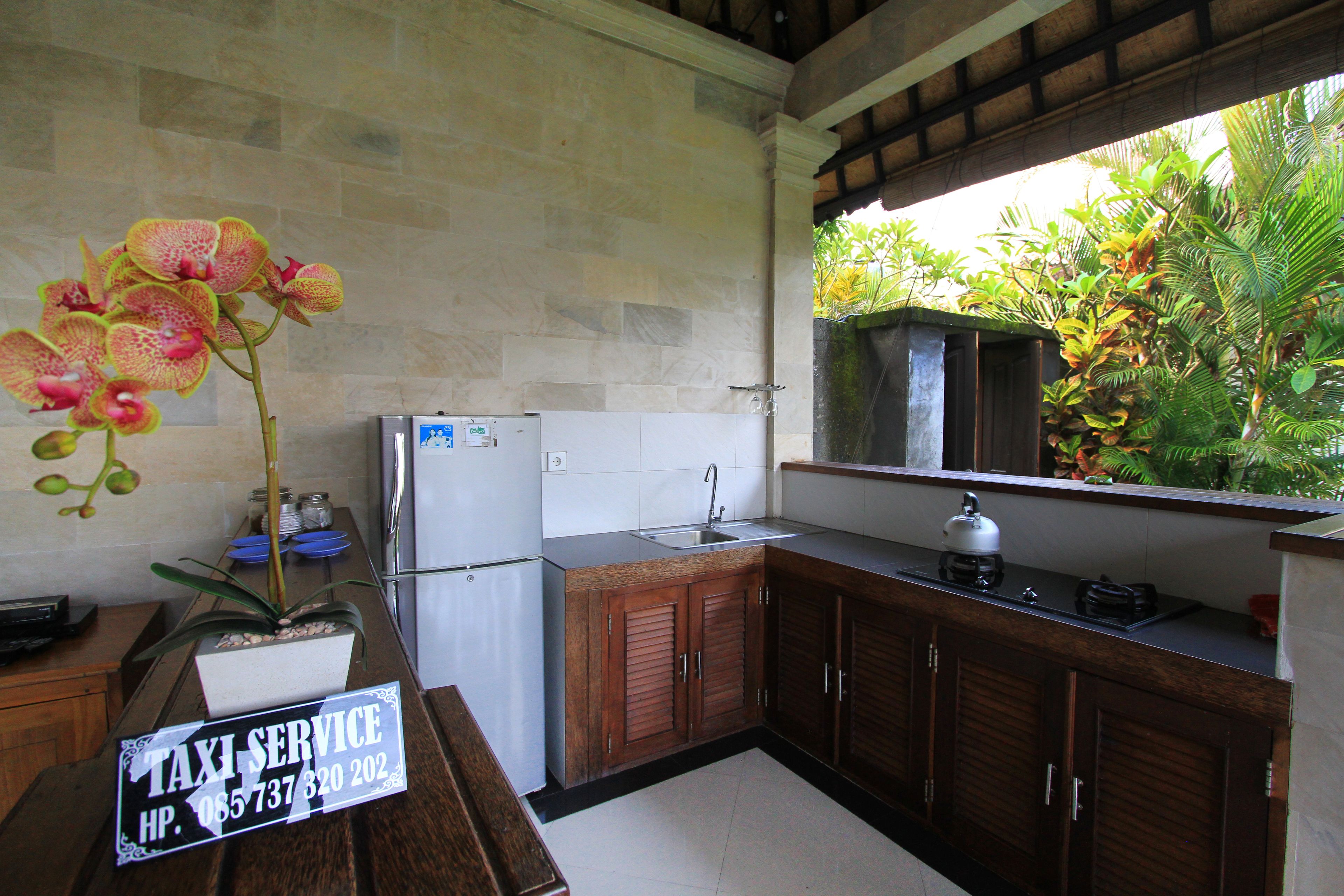 A kitchen with wooden cabinets, a refrigerator, a sink, and a potted orchid.
