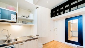 Une cuisine de taille réduite, équipée d’un évier, d’une cuisinière et d’étagères.