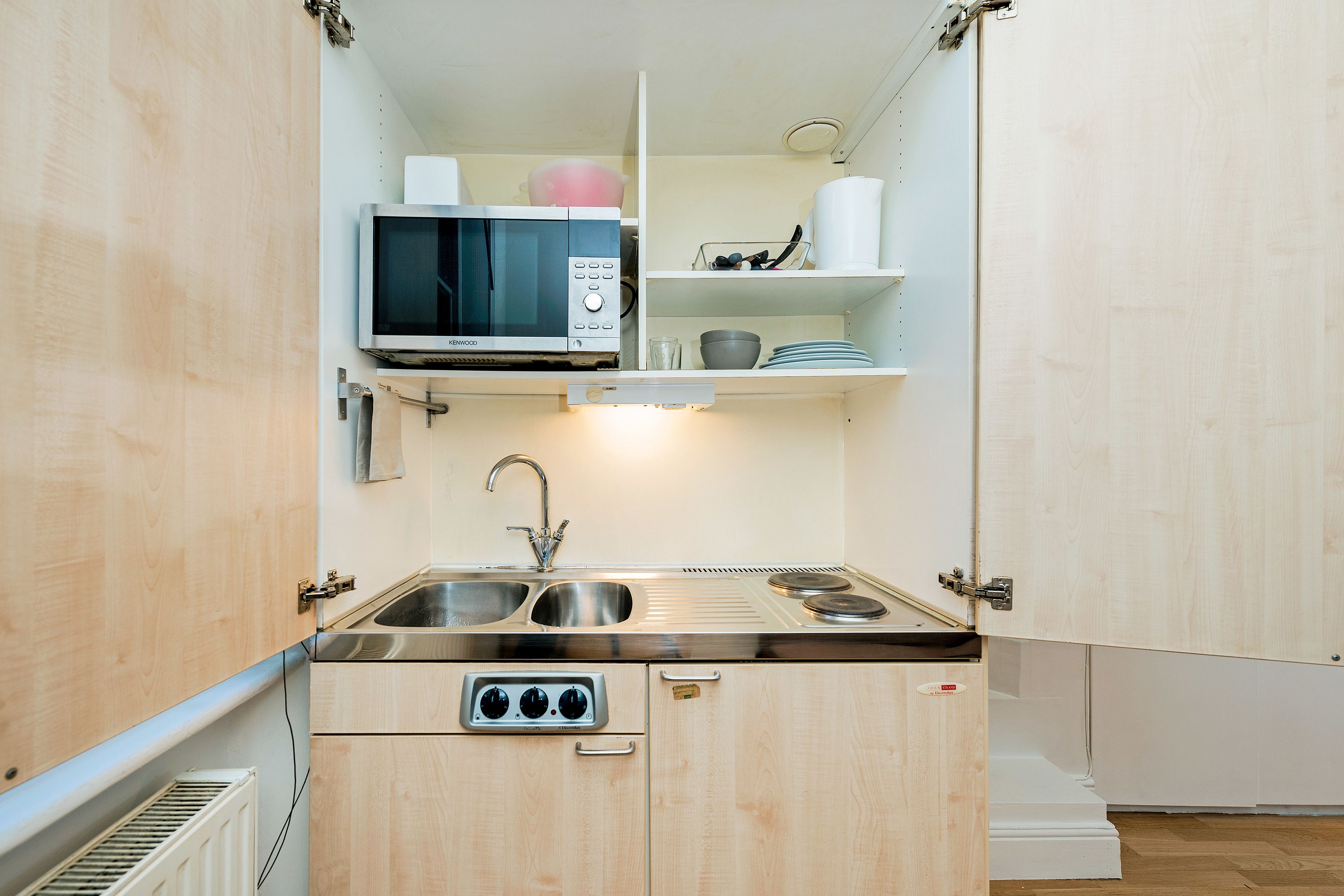 A compact kitchen with a microwave, sink, and built-in oven.