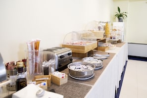 Una mesa de buffet con diferentes opciones de comida, un tostador y una estación de café.