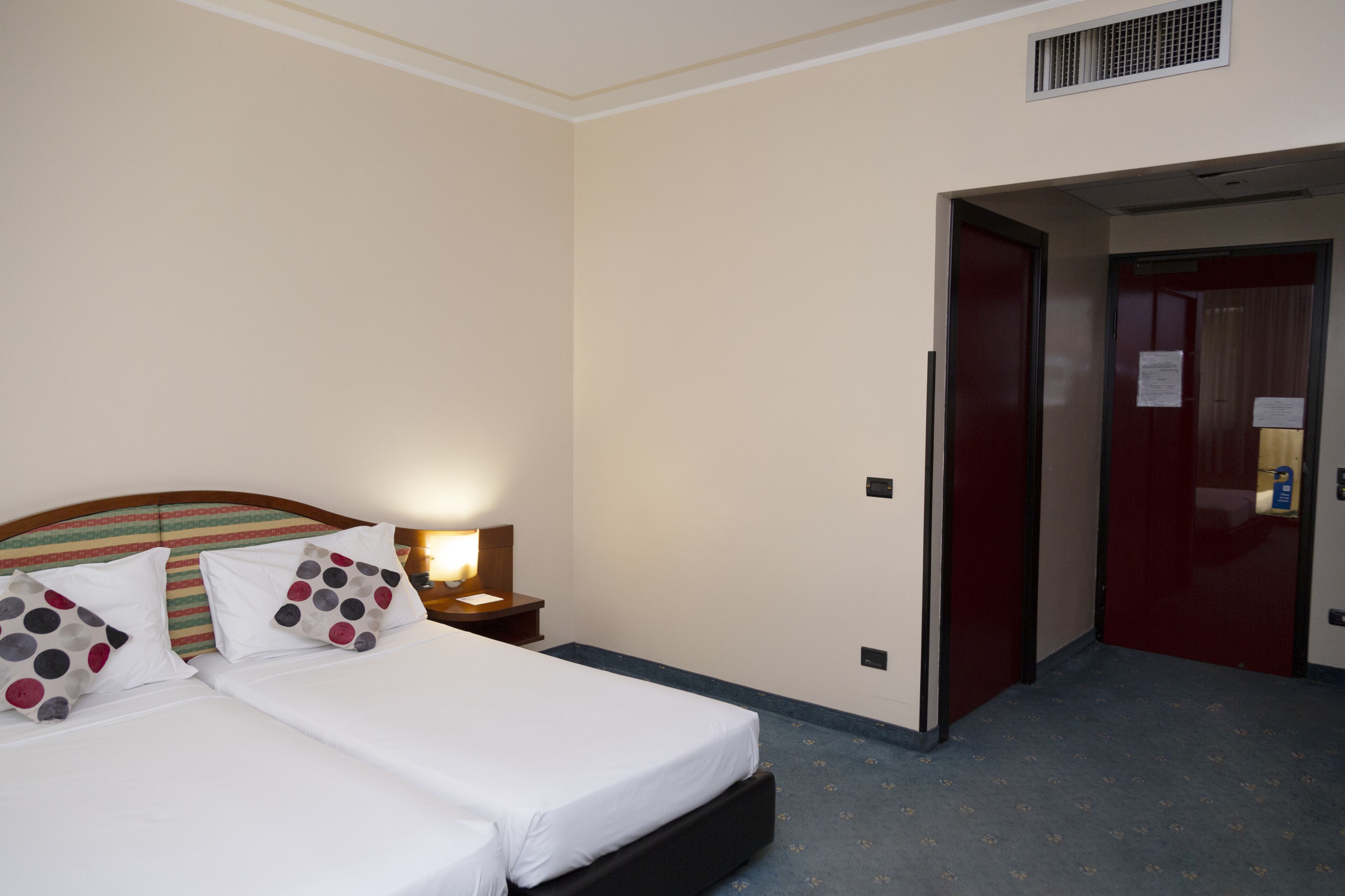 A hotel room with a bed, nightstands, and a door leading to another room.