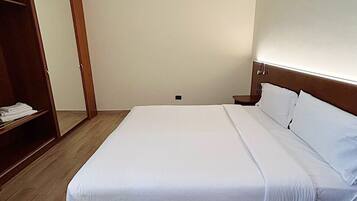 A bedroom with a bed, wooden wardrobe, and a mirror.
