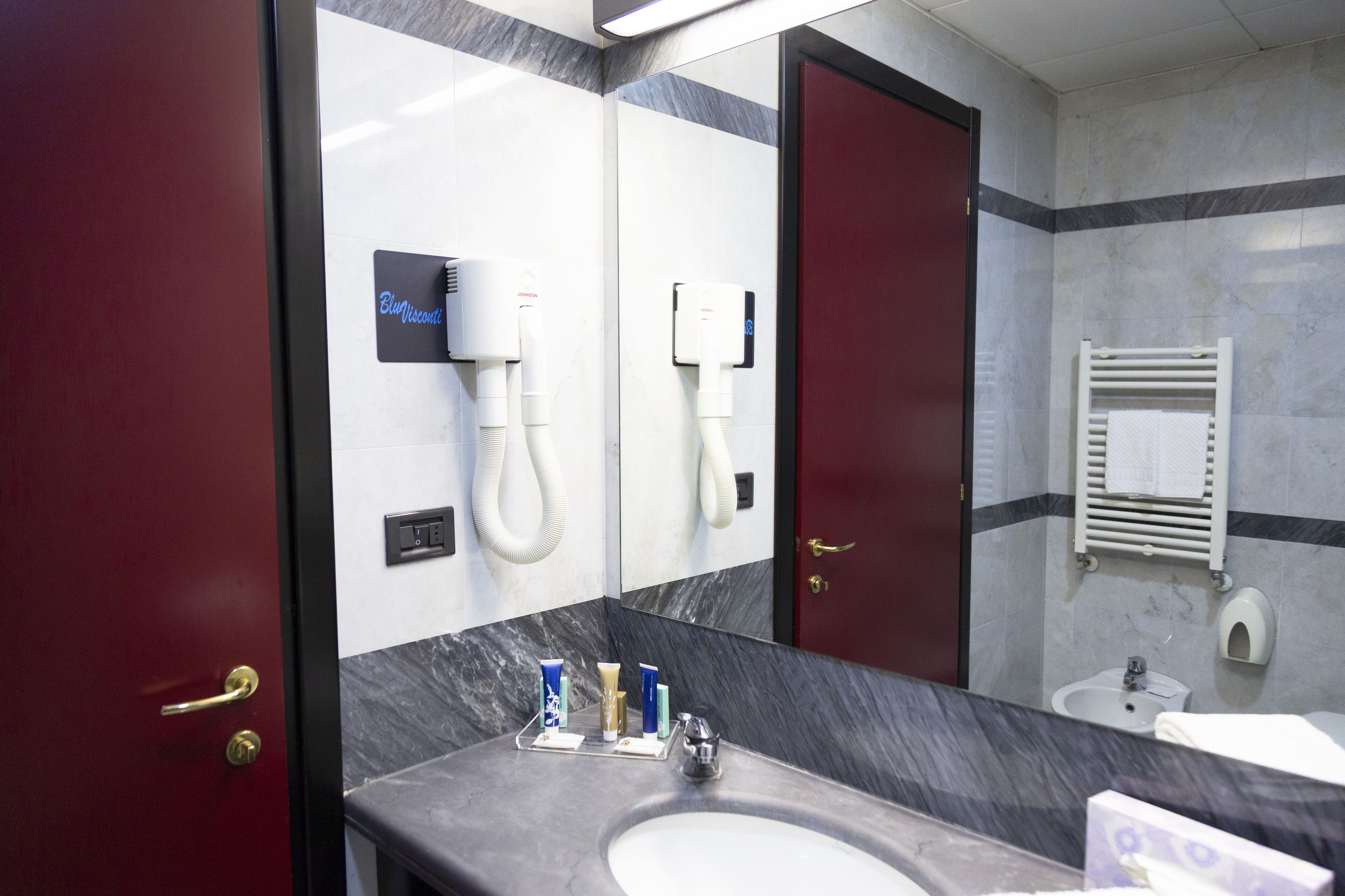 A bathroom with a marble sink, a mirror, a hairdryer, and a towel rack.