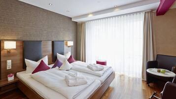 A hotel room with two beds, a desk, and a chair.
