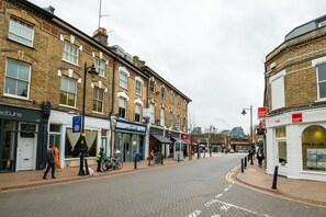 A street with brick buildings, shops, and a pedestrian crossing. - Immaculate Designer Home in Wandsworth (London)