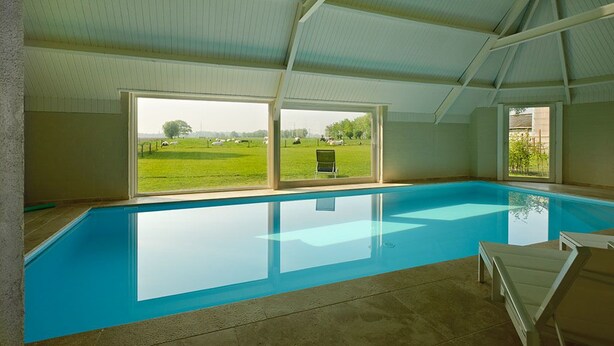 An indoor swimming pool with clear windows, a tiled floor, and a simple, clean design. - B&B Het Weiland (Damme)