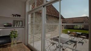 A modern room with a large glass window, a wooden table, and a bench. - B&B Het Weiland (Damme)