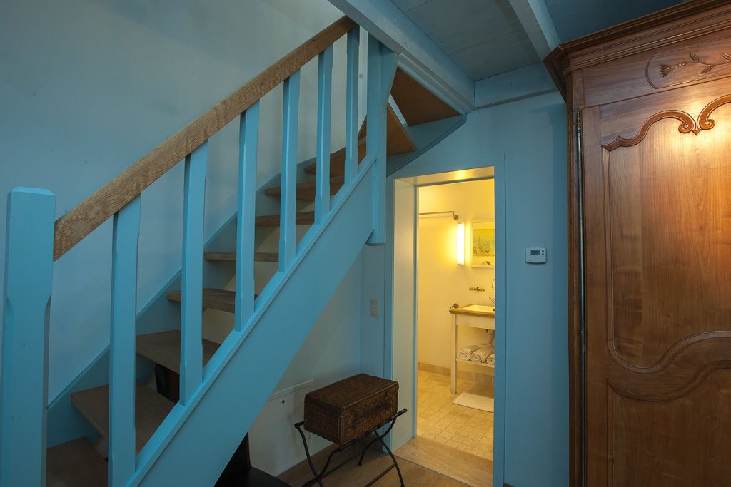 Una escalera con barandas azules que conduce a un baño con lavamanos e inodoro.