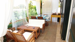 A sunlit patio with wooden furniture, a small table, and a view of greenery. - Forest&Sea apartment-Bikes&table incl (Medulin)