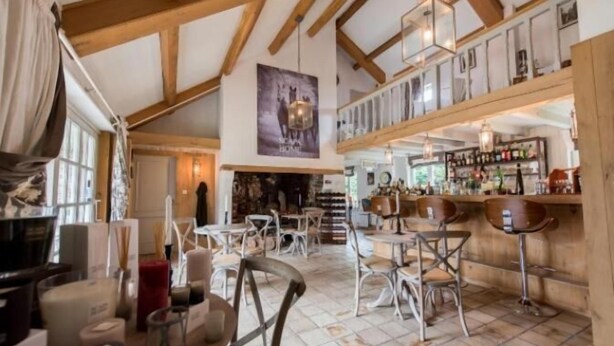 A spacious bar area with high wooden beams, multiple seating options, and a variety of bottles on shelves. - Casa Ciolina (Peer)