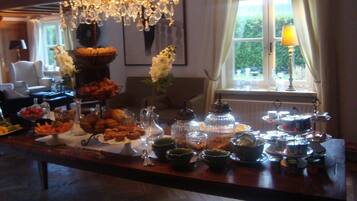 A buffet table with various food items and a chandelier in the background.