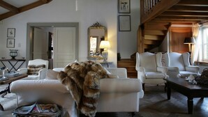 A spacious living room with high ceilings and exposed wooden beams, featuring a fireplace, comfortable seating, and a staircase leading to an upper level. - Casa Ciolina (Peer)