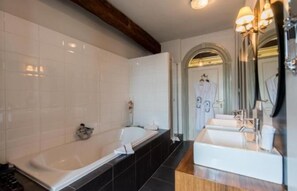 A modern bathroom with a large bathtub, a separate sink, and a vanity mirror. - Casa Ciolina (Peer)