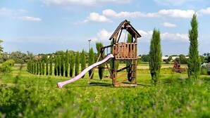 Una estructura de juego de madera con un tobogán en un campo cubierto de césped.