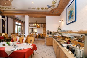 A restaurant with multiple dining tables, a buffet area, and a view of the dining area through a glass partition.
