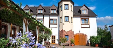 A hotel with a central tower, multiple windows, and a courtyard with potted plants.