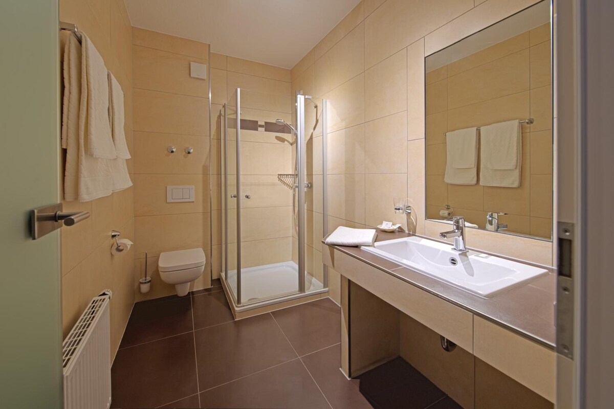 A modern bathroom with a shower, toilet, and sink.