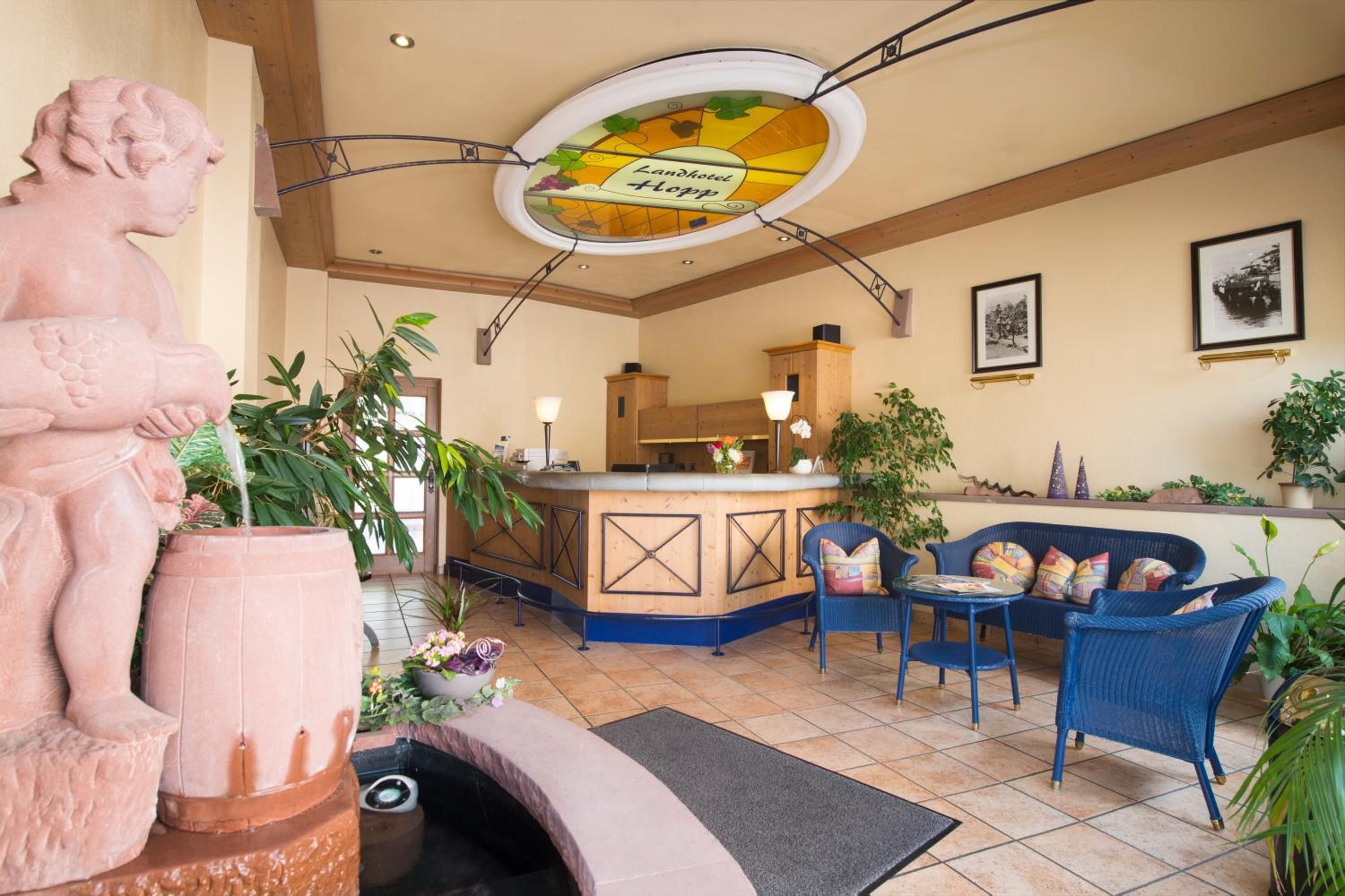 Eine Hotelhalle mit einer Rezeption, einer Sitzecke und einer großen Zierurne.