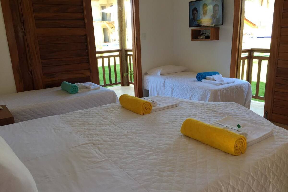 A hotel room with two beds, each with a white quilted bedspread and rolled towels.