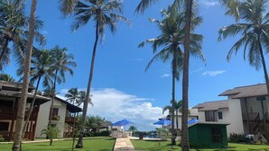 Un resort con varias edificaciones, palmeras y un cielo azul despejado.