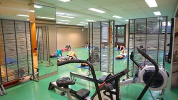A gym with exercise equipment, mirrored walls, and green flooring.