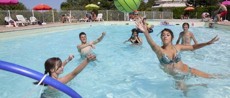 A swimming pool with people playing volleyball.