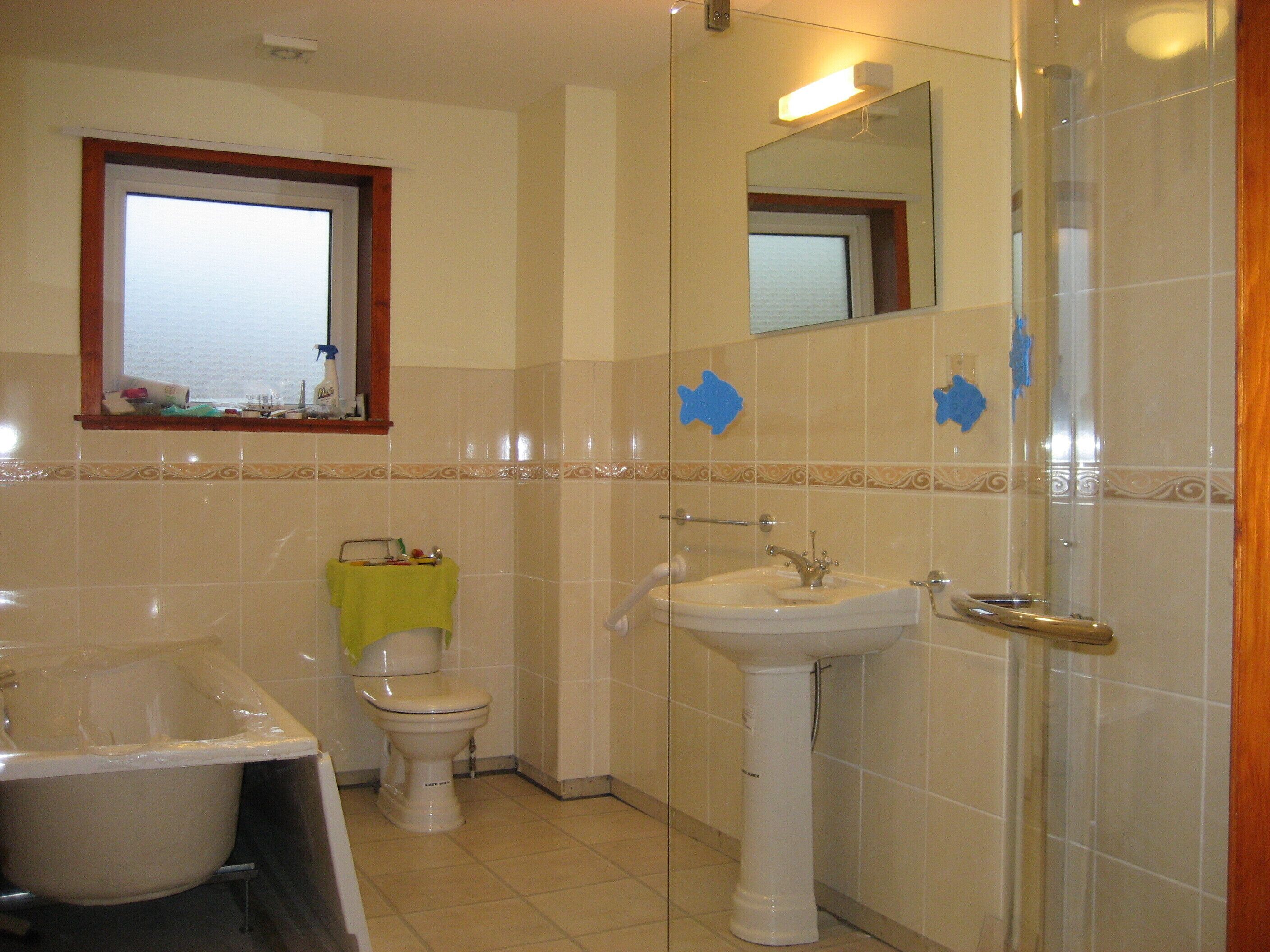 A bathroom with a bathtub, toilet, sink, and a window with a view.