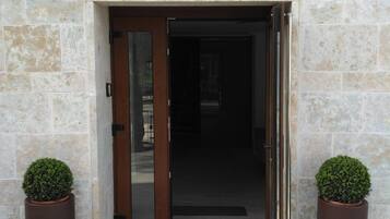 L’entrée d’un hôtel, avec une façade en pierre, une porte en bois et deux plantes en pot.