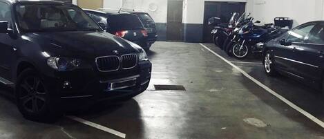 A parking garage with multiple cars and motorcycles.
